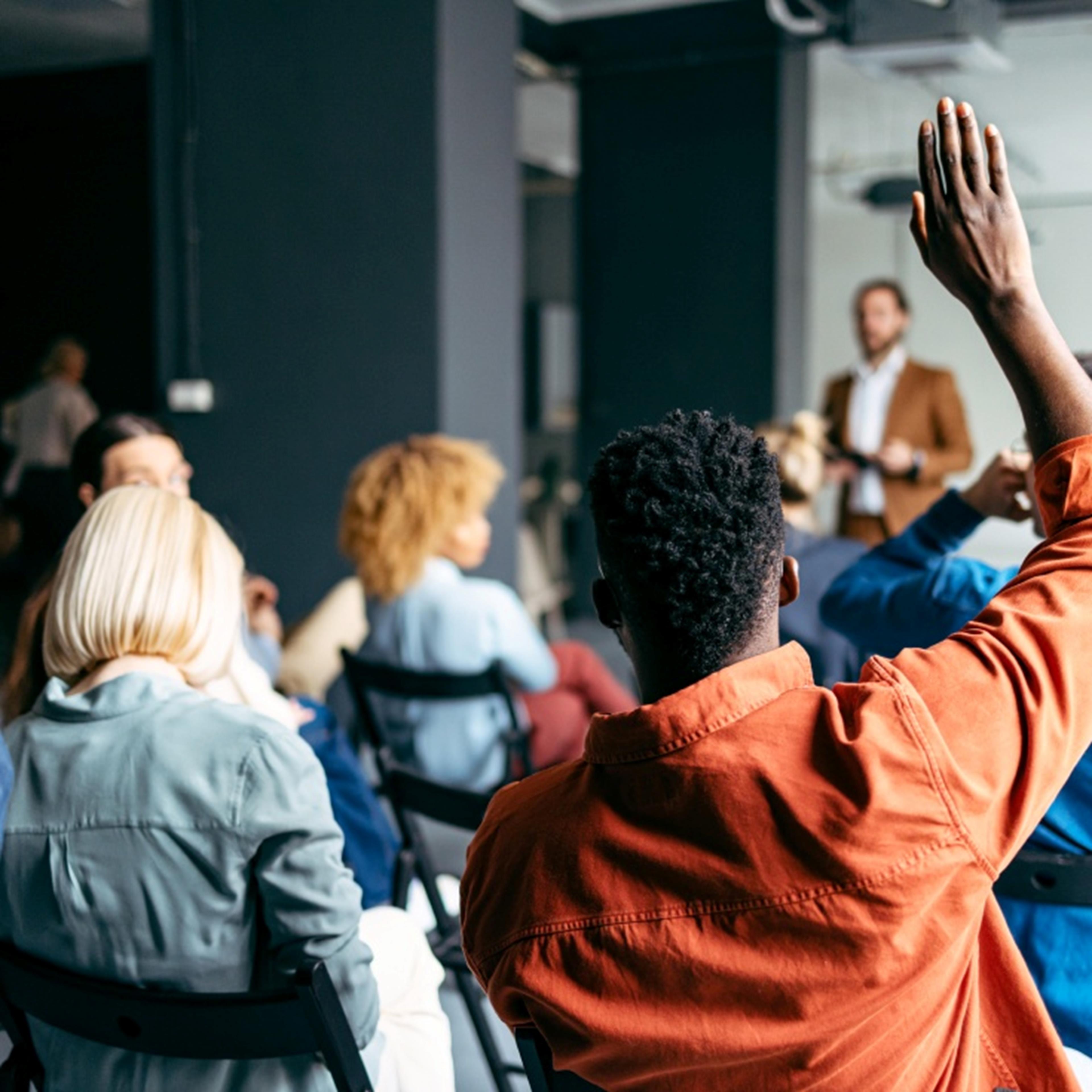 young man raising his hand in a classroom